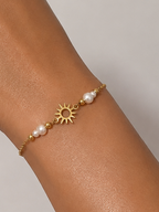 Close-up of a gold sun charm bracelet with 2 mm and 4 mm white baroque freshwater pearls