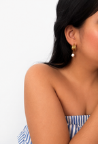 Woman wearing a gold triple-hoop earring with a white baroque freshwater pearl drop