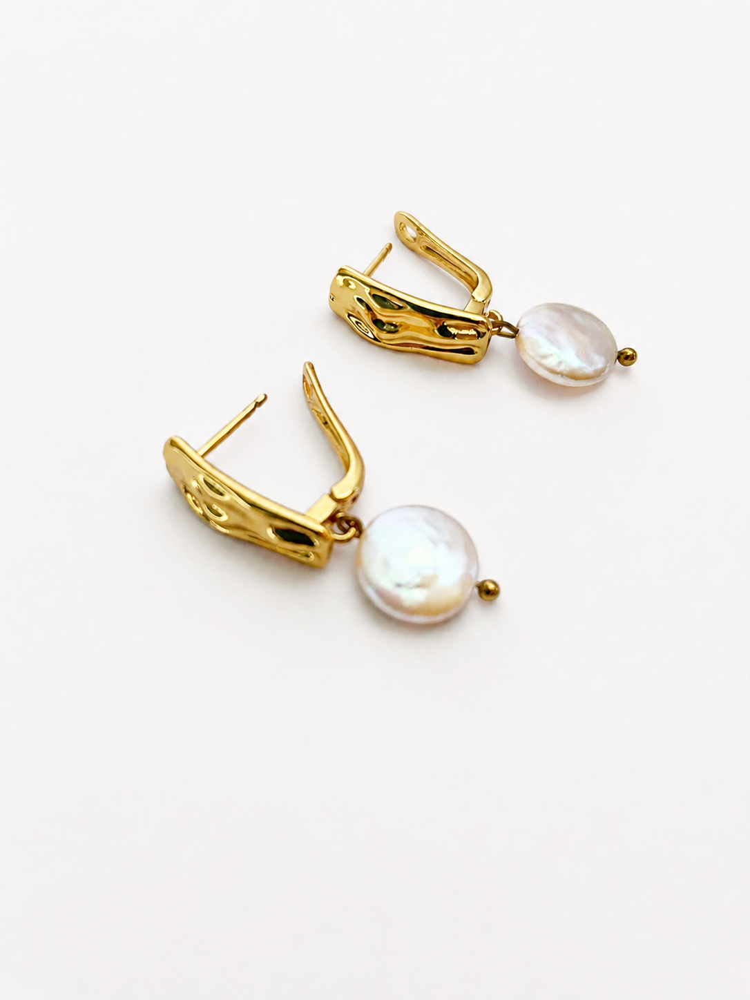 Close-up of gold rectangle drop earrings with luminous white freshwater coin pearls