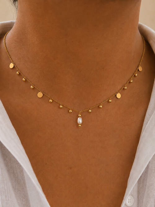 Close-up of a gold bead charms necklace with a 6 mm oval white freshwater pearl worn on the neck