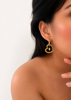 Close-up of a gold heart drop earring with a 6 mm oval white freshwater pearl worn on the ear