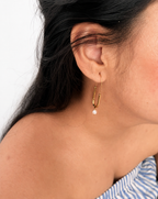 Woman wearing a gold paperclip drop earring with a 5 mm white freshwater pearl pendant