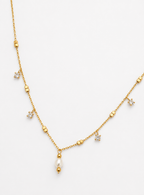 Close-up of a gold chain necklace with a white freshwater pearl pendant and brilliant-cut cubic zirconia accents.