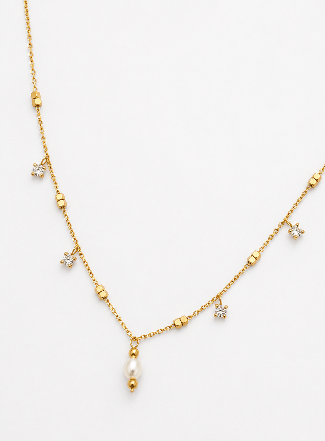 Close-up of a gold chain necklace with a white freshwater pearl pendant and brilliant-cut cubic zirconia accents.