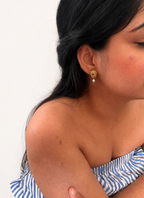 Woman wearing a sculptural gold spiral earring with a white freshwater pearl drop.