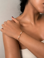 Woman wearing a delicate gold chain bracelet with white and champagne baroque freshwater pearls