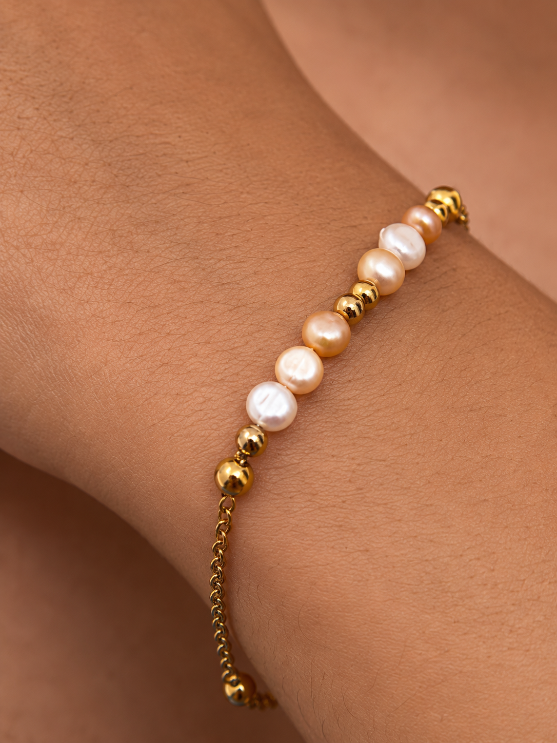 Close-up of white and gold-toned baroque freshwater pearls with polished gold beads on a bracelet