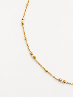 Close-up of a delicate gold chain necklace with petite white Keshi freshwater pearls and polished gold beads