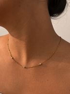 Woman wearing a delicate gold necklace with 2 mm white Keshi cultured freshwater pearls and gold bead accents