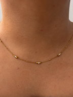 Front view of a delicate gold necklace with 2 mm white Keshi freshwater pearls spaced along the chain