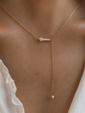 Close-up of a gold Y-necklace with graduated white Keshi freshwater pearls worn on the neck.