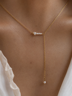Close-up of a gold Y-necklace with graduated white Keshi freshwater pearls worn on the neck.