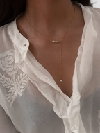 Woman wearing a gold lariat Y-necklace with graduated white Keshi freshwater pearls.