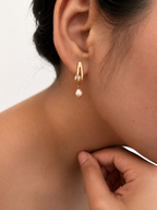 Back and angled view of gold huggie earrings with oval and baroque white freshwater pearls and stud posts.