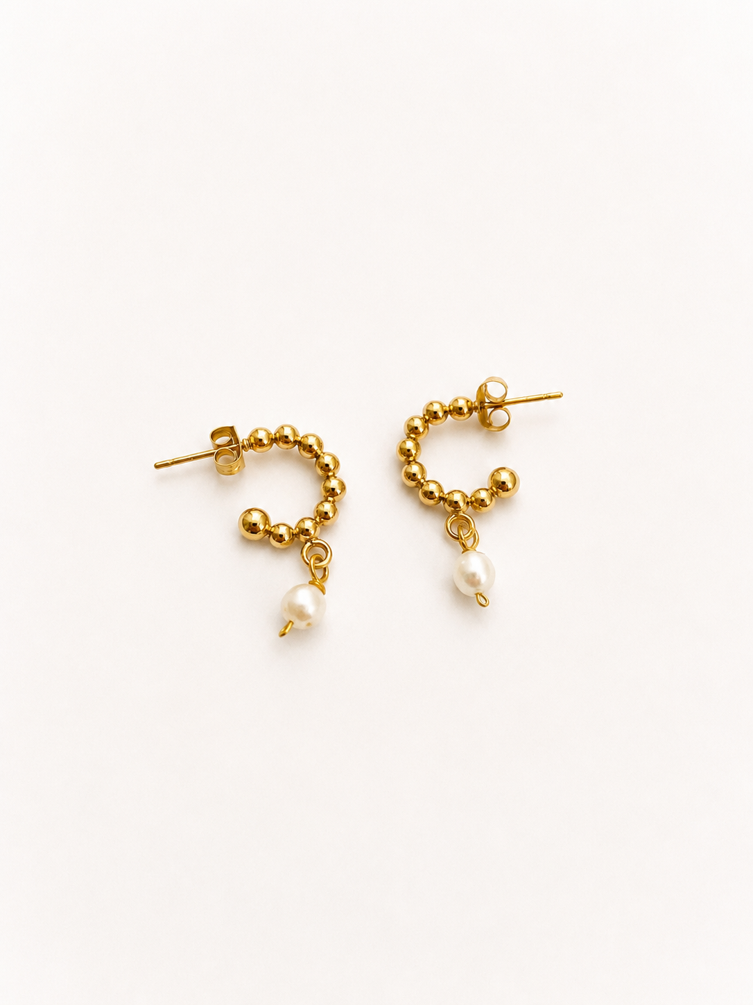 Pair of beaded gold huggie earrings with 6 mm oval white freshwater pearl drops.