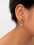 Close-up of a gold circle drop earring with a 6 mm oval white freshwater pearl worn on the ear