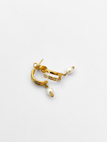 Angled view of gold half moon huggie earrings with 6 mm oval white freshwater pearls and cubic zirconia