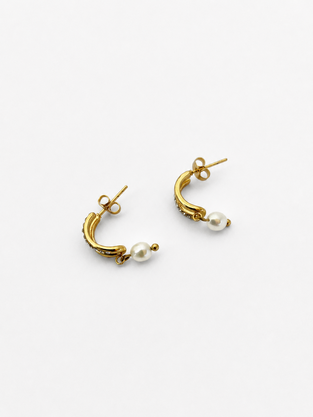 Pair of gold half moon huggie earrings with 6 mm oval white freshwater pearl drops and cubic zirconia accents
