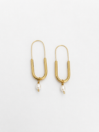 Front view of gold paperclip earrings with oval white freshwater pearl drops