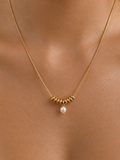 Close-up of a gold Ripple necklace with a 5 mm oval white freshwater pearl worn on the neck.