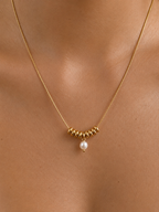 Close-up of a gold Ripple necklace with a 5 mm oval white freshwater pearl worn on the neck.