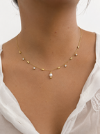 Woman wearing a gold necklace with a 5 mm oval white freshwater pearl and sparkling cubic zirconia accents.