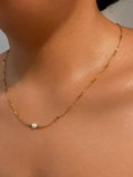 Close-up of a gold Waves necklace with a 6 mm oval white freshwater pearl worn on the neck