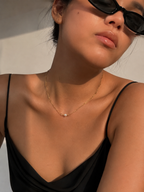 Lifestyle view of a gold Waves necklace with an oval white freshwater pearl and delicate textured chain