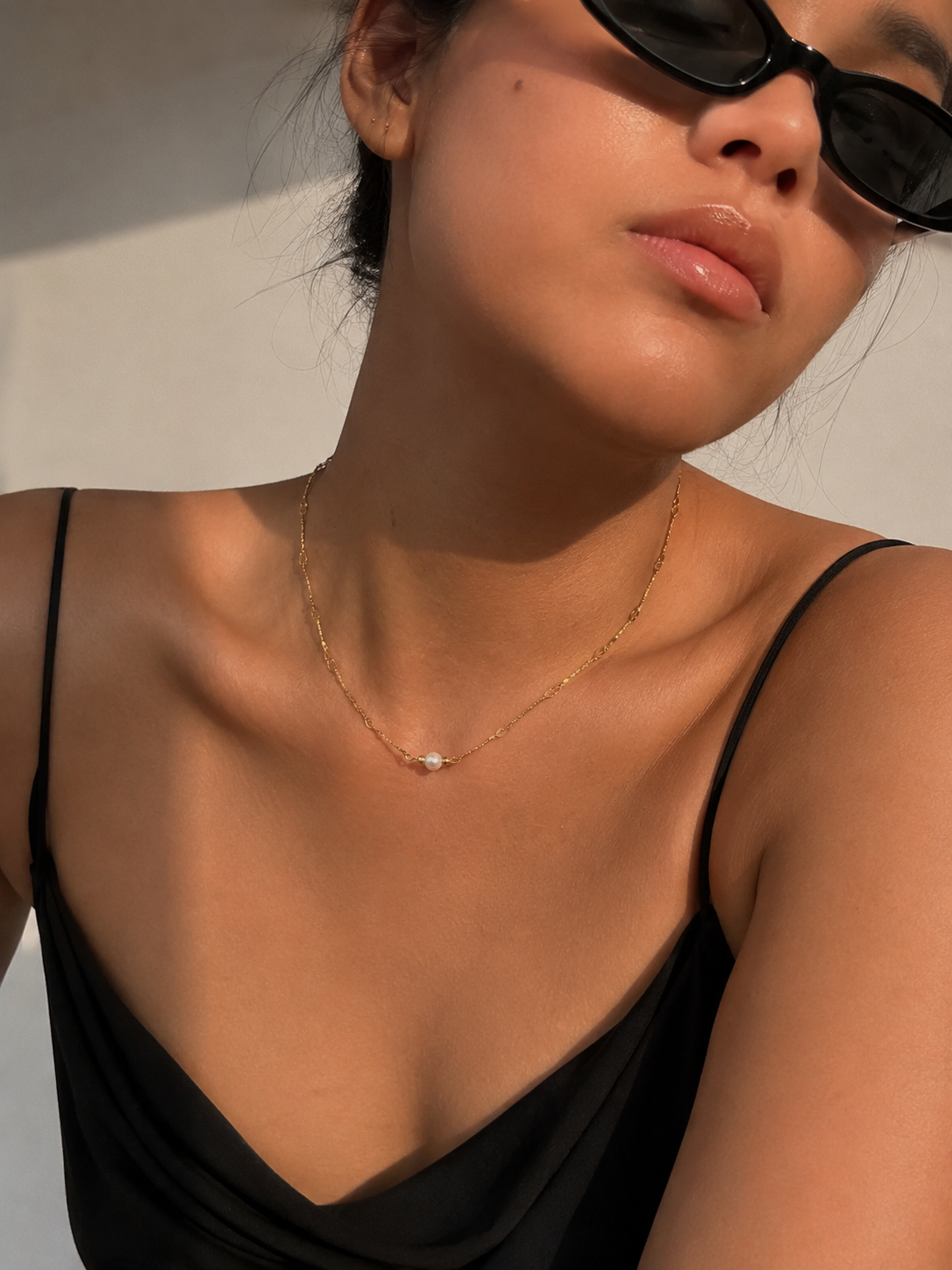 Lifestyle view of a gold Waves necklace with an oval white freshwater pearl and delicate textured chain