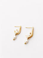 Back and angled view of gold huggie earrings with oval and baroque white freshwater pearls and stud posts