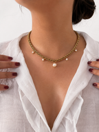 Woman wearing a chunky gold statement necklace with white freshwater pearl charms and a central Baroque pearl.